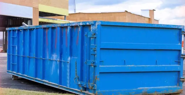 Blue roll-off dumpster left on a job site for scrap collection